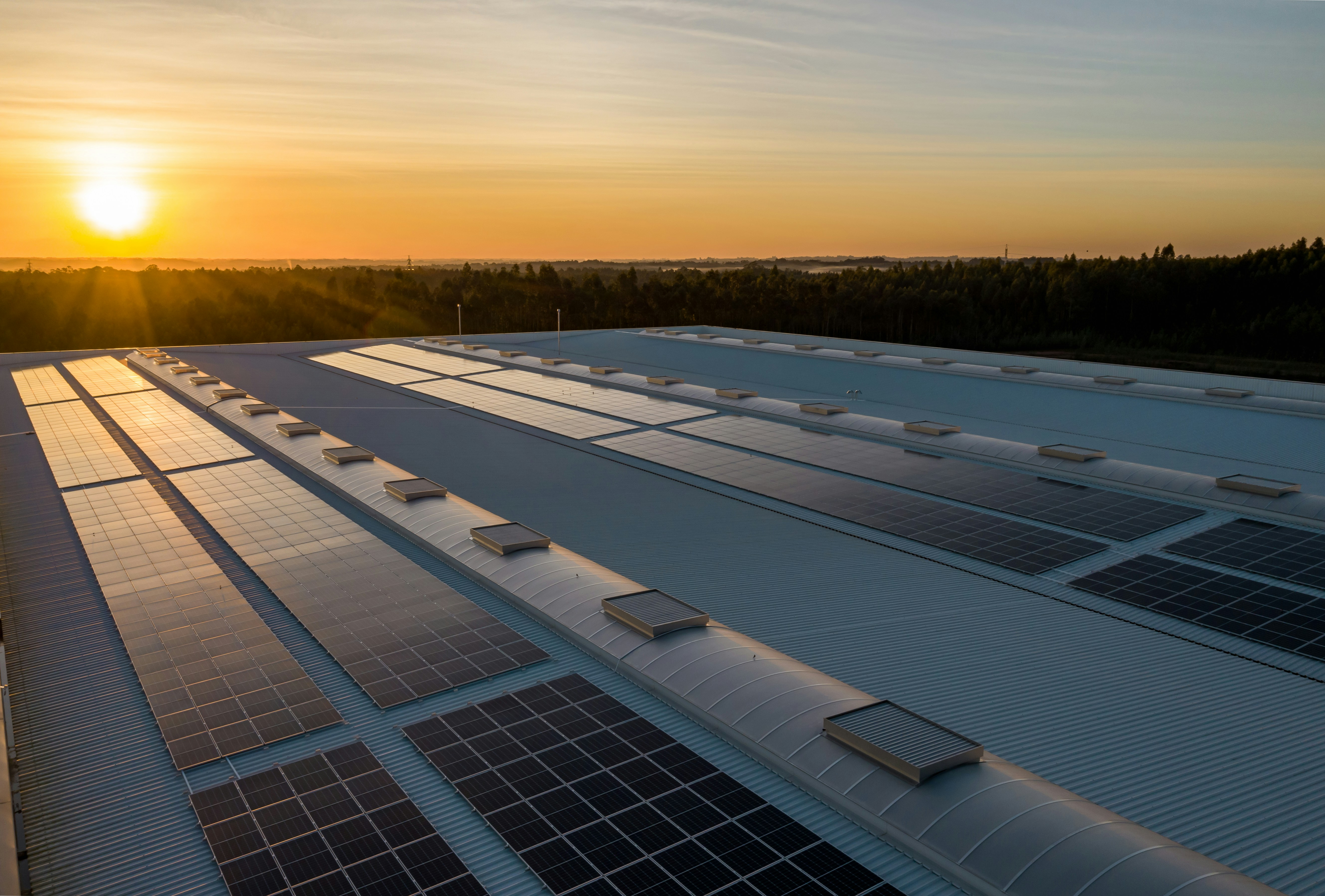 Aerial view of a large data centre rooftop covered in solar panels at sunset